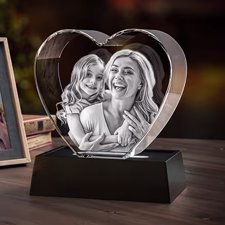 Herzförmiger 3D-Fotokristall mit eingraviertem Porträt einer Mutter und ihrer Tochter, präsentiert auf einem schwarzen LED-Lichtsockel.