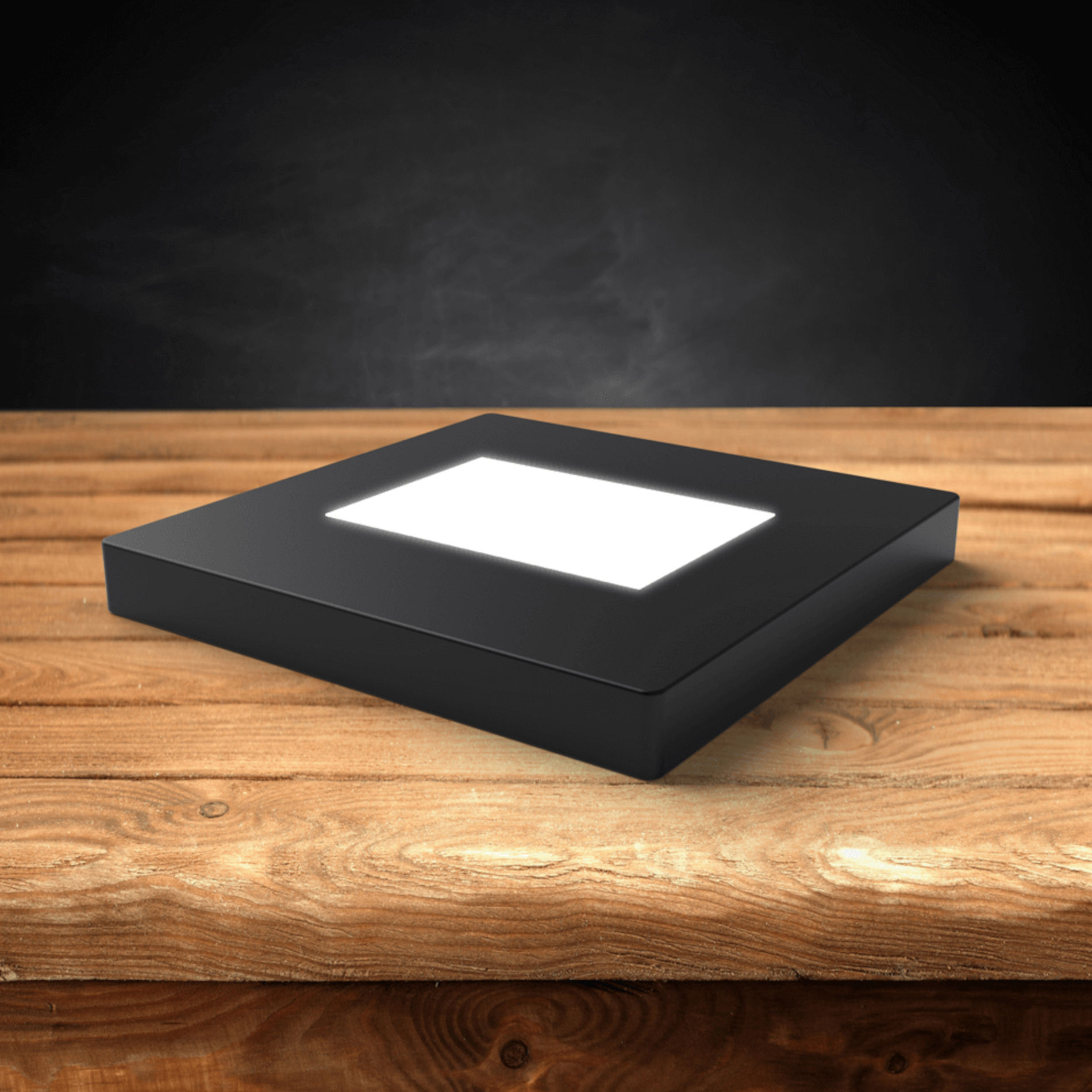 Dunkler LED-Lichtsockel aus Holz auf einem Holztisch.